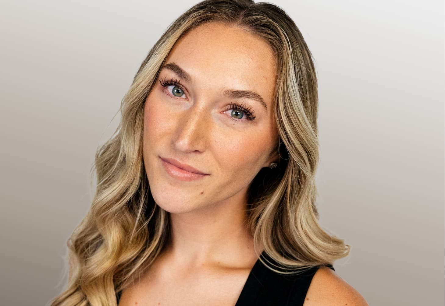 Young woman with fair skin, blonde hair, and green eyes staring forward.