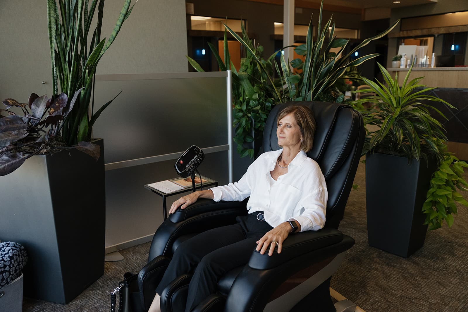 Patient sitting on a black recliner chair in Sutton Dermatology + Aesthetics