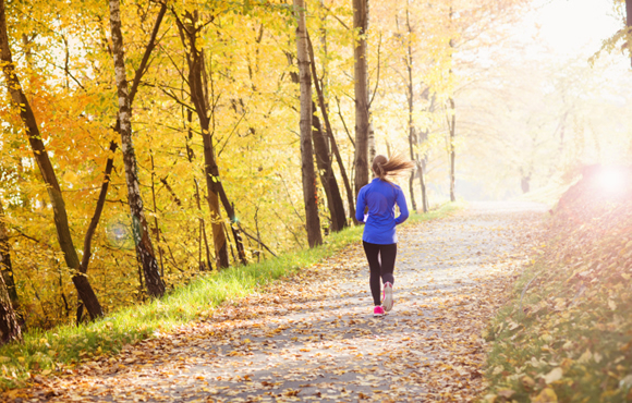 Woman running down a road in the fall season