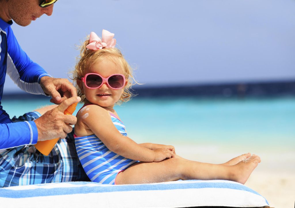 Parent applying sunscreen onto child