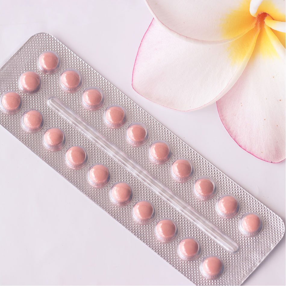 Pink birth control pills in their prescription plastic