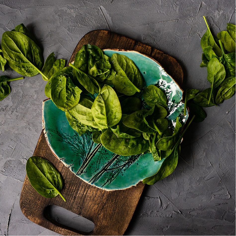 Spinach laying on a wooden cutting board