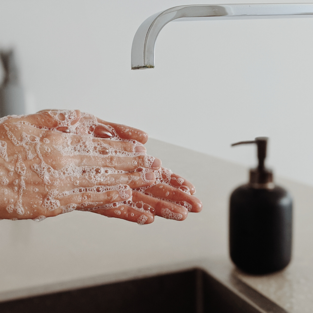 cropped image of soapy hands at sink