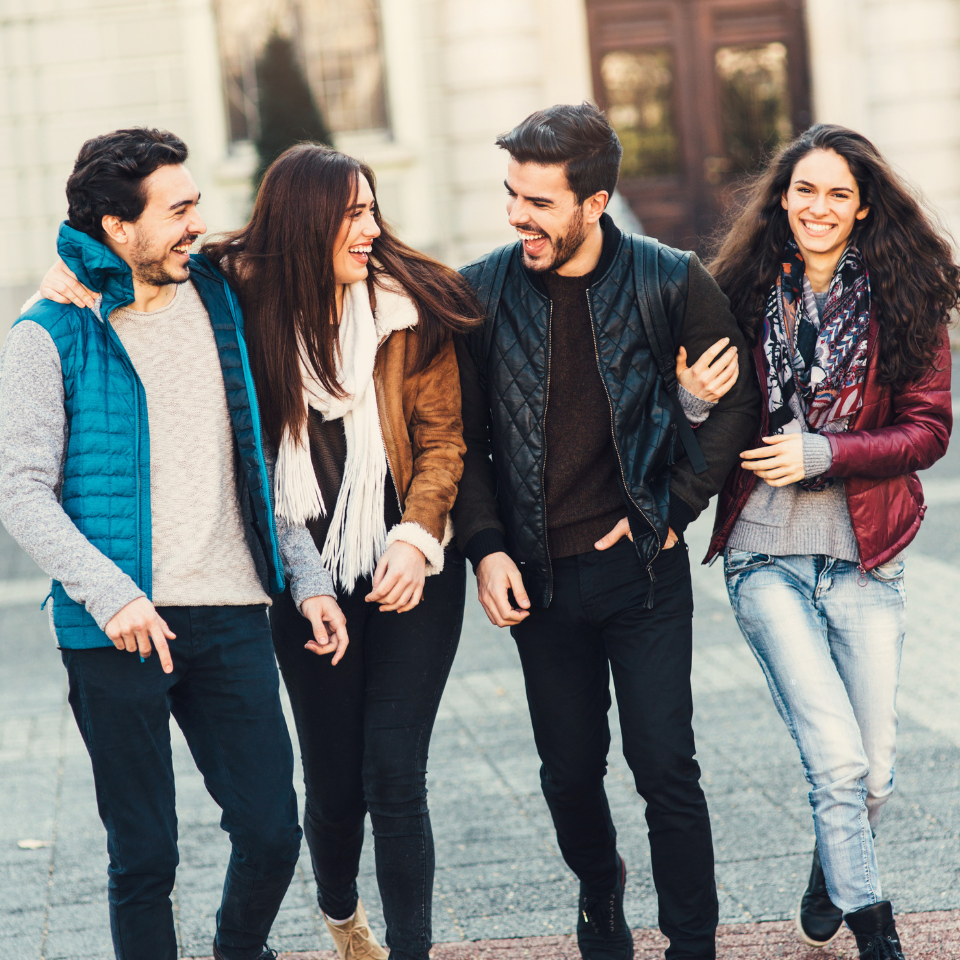 two men and two women locked arms walking together looking happy