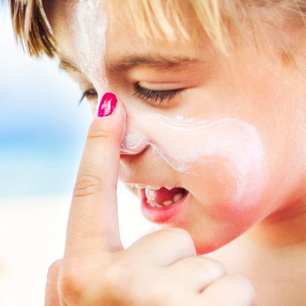 parent hand putting sunscreen on male child face