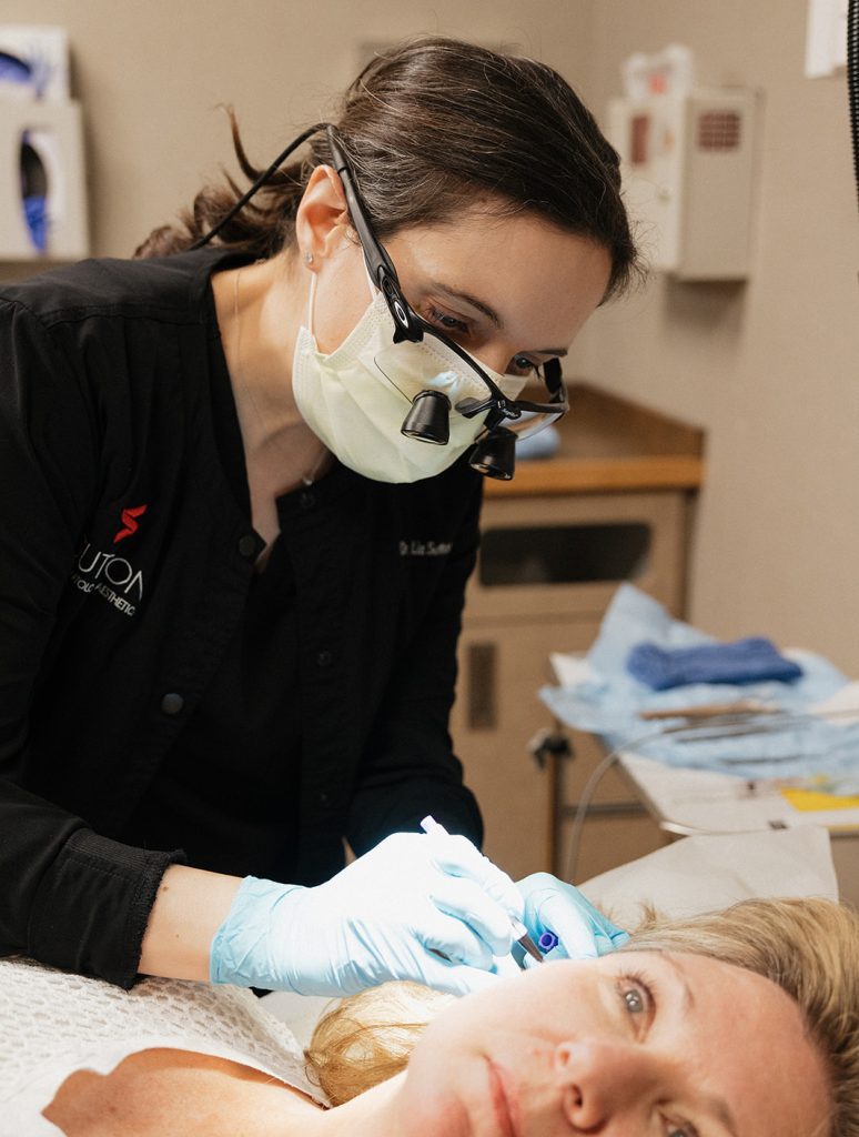 Dr. Liz Sutton in full surgical garb operating on a patient