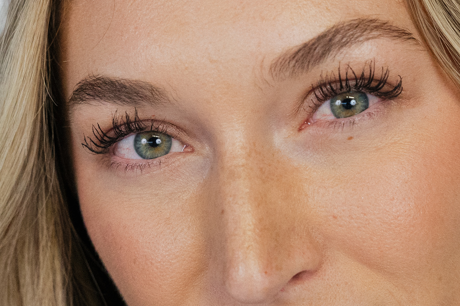 Woman with blonde hair, green eyes, and fair skin staring forwards