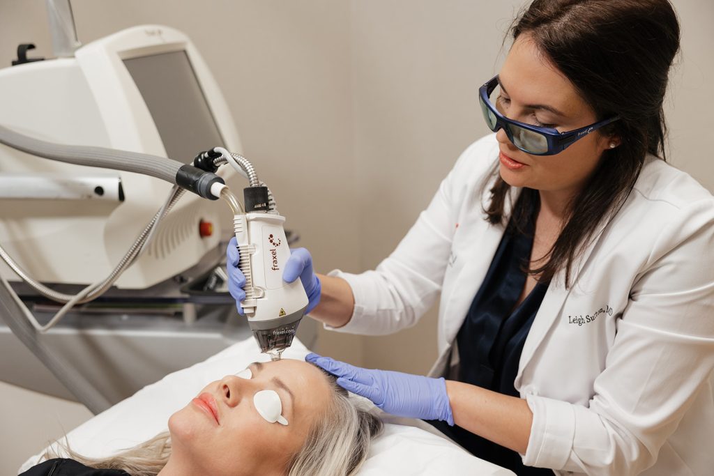 Patient lying down with eye covers receiving fraxel laser treatment from Dr. Leigh Sutton