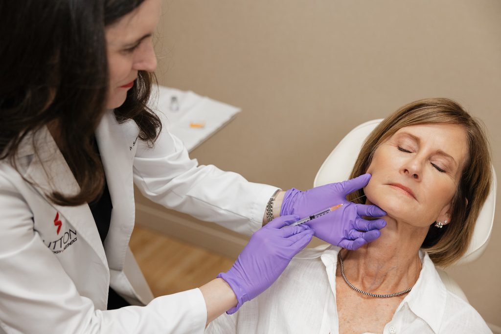 Dr. Elizabeth Sutton applying filler solution through a syringe to a patient's chin