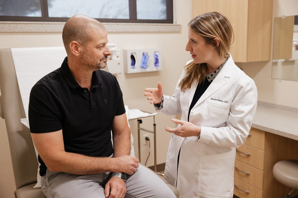 Dr. Jessica Harms speaking to client wearing black polo