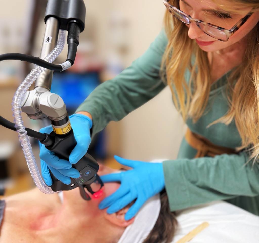 Sutton Dermatology and Aesthetics provider using the CoolPeel machine on a patient's cheek