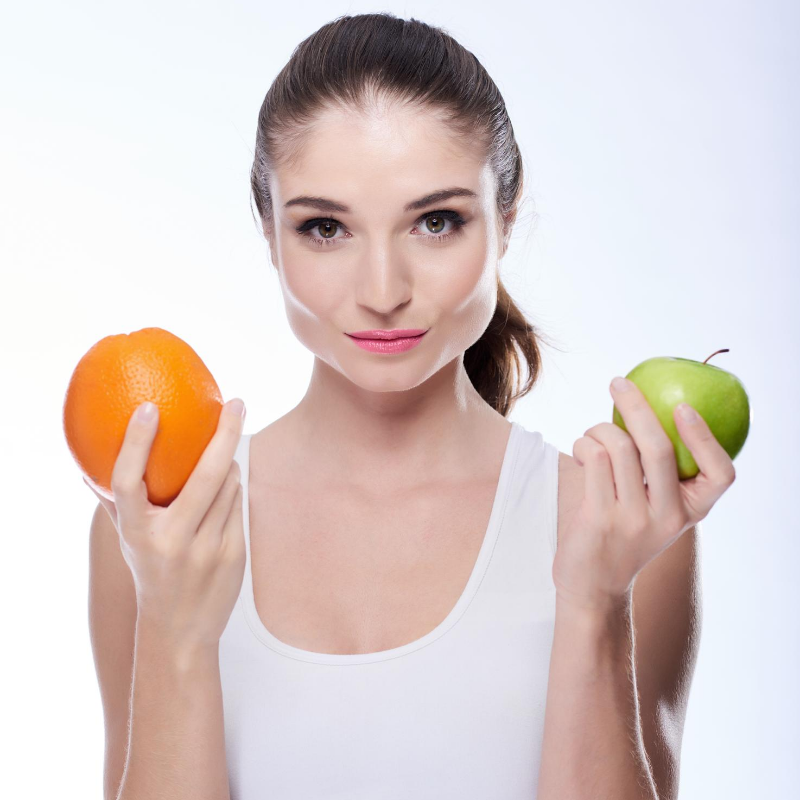 woman holding an orange in one hand and apple in the other