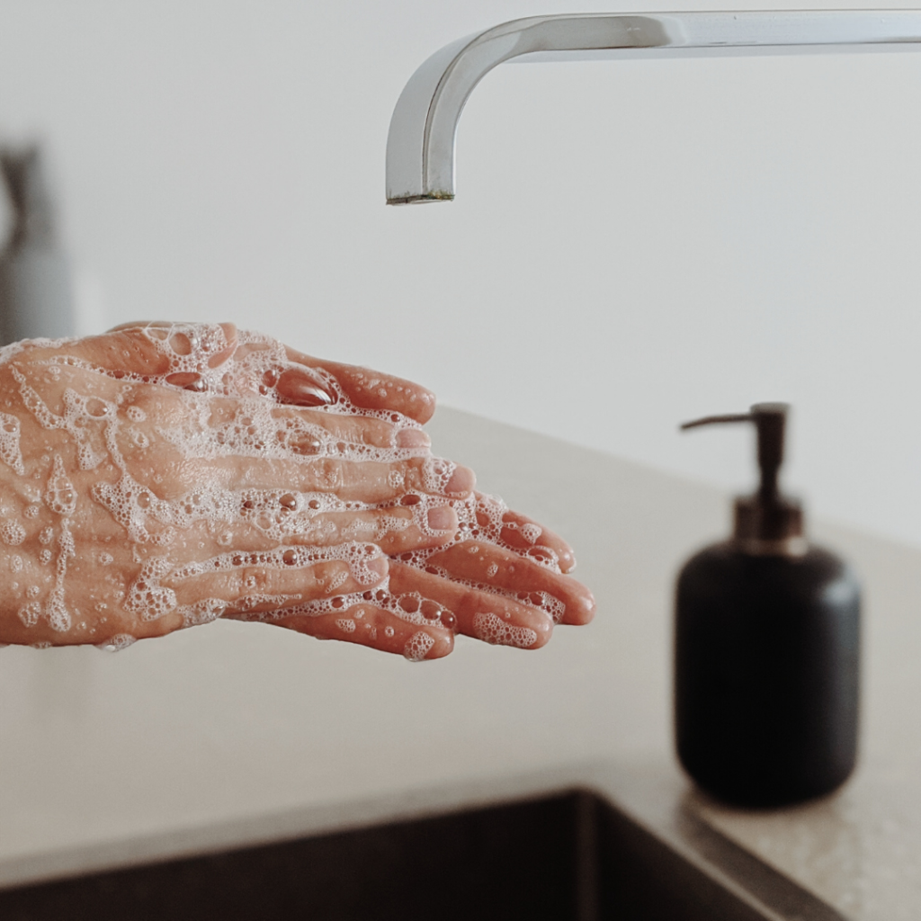 cropped image of soapy hands at sink